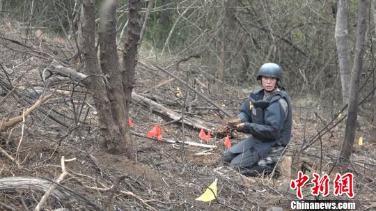 图为扫雷官兵从泥土中刨出地雷。 张广权 摄