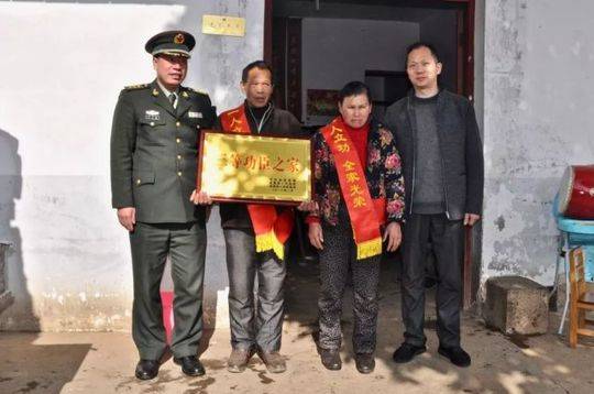 ▲金溪籍军人邓长文的父母手捧功臣牌匾,身披“一人立功、全家光荣”红绶带。