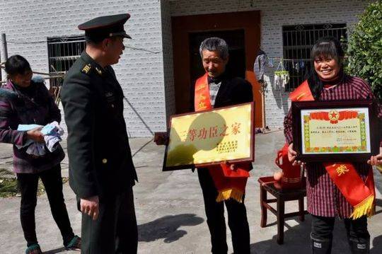 ▲金溪籍军人王影坤父母手捧喜报和牌匾,旁边的邻居很是羡慕。