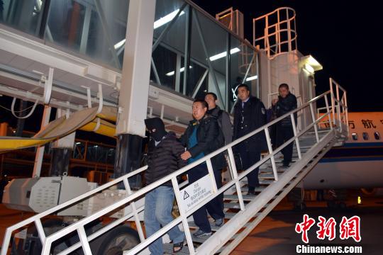 图为12月8日晚,“红通”逃犯杨国庆被兰州警方押解返回兰州。 魏存武 摄
