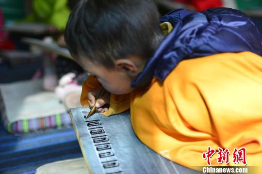 图为正在以传统方式练习藏文书法的藏族小学生。 周文元 摄