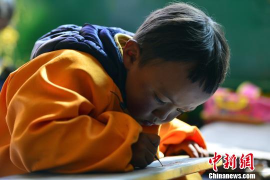 传统的藏文书法练习方式要求练习者盘腿而坐,一手按稳墙星,一手书写。 周文元 摄