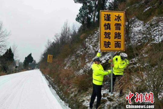 图为两名交警正在冰雪路段设置“冰雪路面”警示标牌。警方供图
