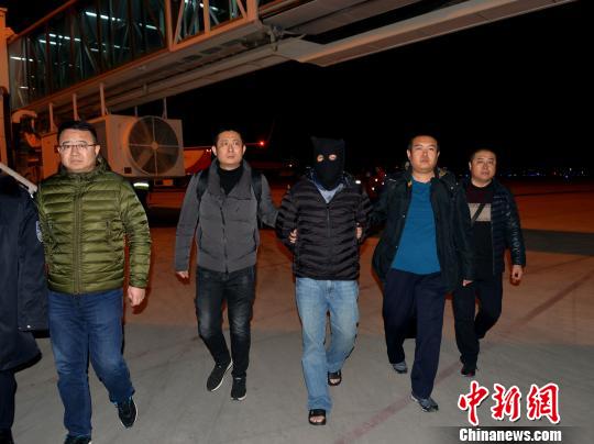 图为12月8日晚,“红通”逃犯杨国庆被兰州警方押解返回兰州。 刘胜男 摄