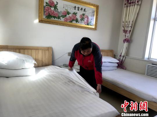 图为姜发菊家开设的家庭宾馆客房内,姜发菊在整理床铺。 孙睿 摄