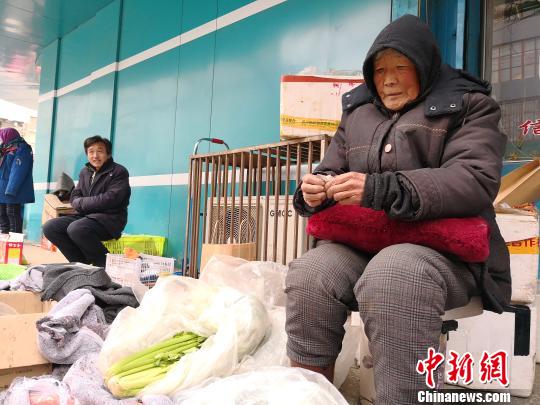 图为张菊芳老人正在卖菜。　甘芬 摄