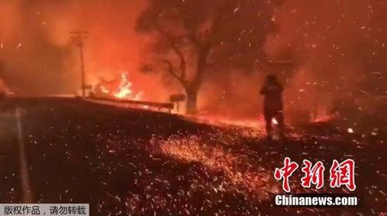 山火借助风力迅速蔓延,图为加州一公路上火星四溅。(视频截图)