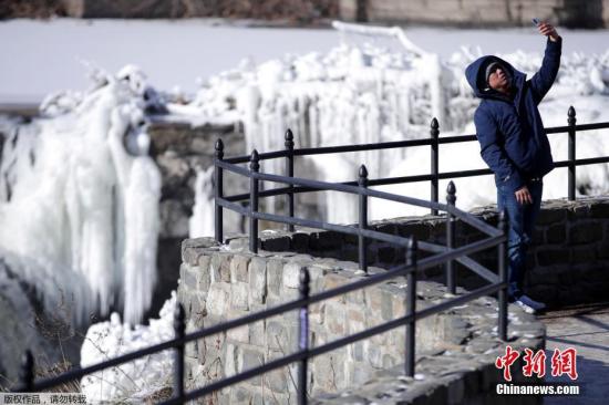 全美日前遭遇极寒天气,多地刷新低温纪录。图为当地时间1月2日,新泽西州东北部城市帕特森的居民Obdulio Arenas举起手机自拍,在他身后是在极寒天气中冻住的瀑布。