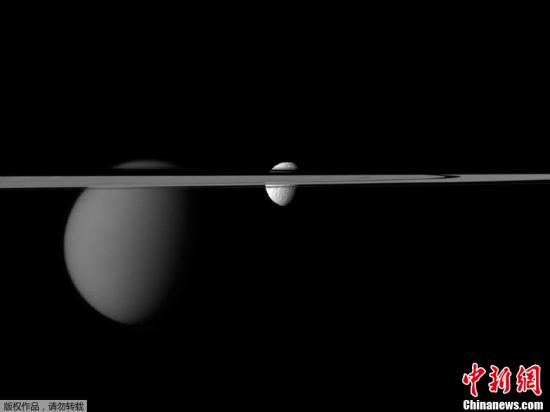 资料图:美国国家航空航天局(NASA)近日公布了“卡西尼”号飞船发回的土星环“横切”两颗土星的卫星、形成“一环穿两珠”奇景的照片。从图片中可以看到,“土卫三”以及土星最大的卫星“土卫六”都正好处在土星环的位置,就如被土星环串起来的珠子一般。