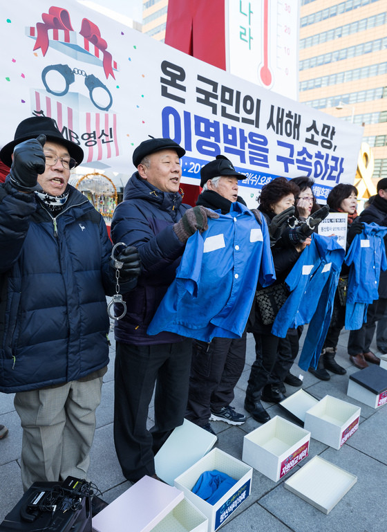 去年12月27日,韩国市民团体手持囚衣要送给李明博