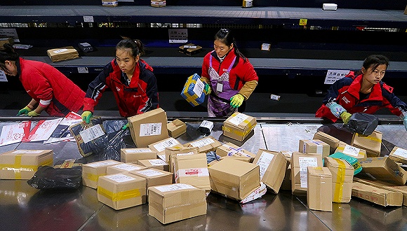 快递员在流水线上分拣包裹。图片来源：视觉中国