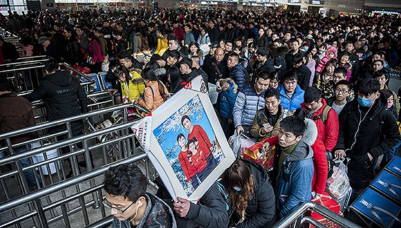 　　2017年1月10日，北京西站检票口，来自安徽省马鞍山市的贾宏俊扛着一张全家福经过检票口。图片来源：视觉中国