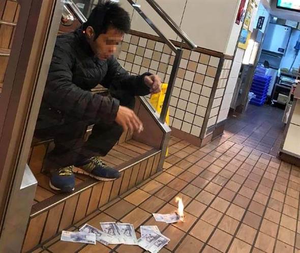 一台湾男子坐在麦当劳的楼梯上焚烧千元新台币(图片来源:“中时电子报”)