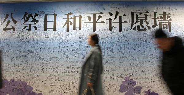 2017年12月11日，江苏省南京市，人们从侵华日军南京大屠杀遇难同胞纪念馆旁云锦路地铁站的国家公祭和平许愿签名墙前走过。 东方IC 图