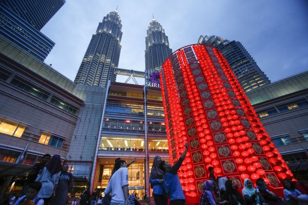 2016年2月5日，吉隆坡双子塔前竖立起“灯笼塔”迎接中国农历猴年春节。图为民众在双子塔前和“灯笼塔”合影。新华社/美联