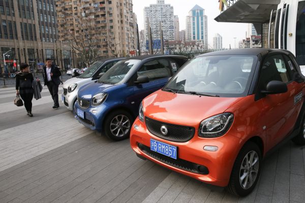 资料图片：2月16日，在上海曲阜路街头，行人经过路旁的“共享汽车”。新华社记者 丁汀 摄