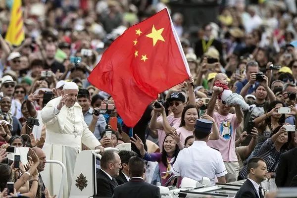 ▲资料图片：2016年6月，圣彼得广场上，有人在教皇方济各身畔挥舞着中国国旗。（《纽约时报》网站）