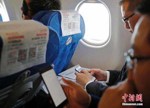 旅客在东航航班上操作便携电子设备。 中新网 图