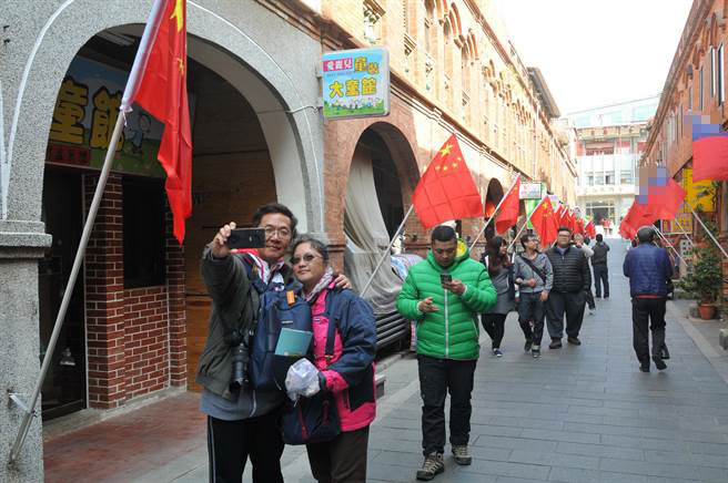 金门“模范街”两旁插满两岸旗帜，两岸游客驻足拍照。（图片来源：台湾“中时电子报”）