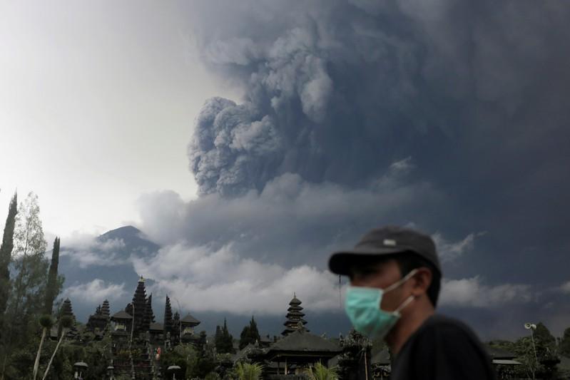 巴厘岛阿贡火山喷发大量火山灰到空中，当地民众戴口罩防吸入火山灰。