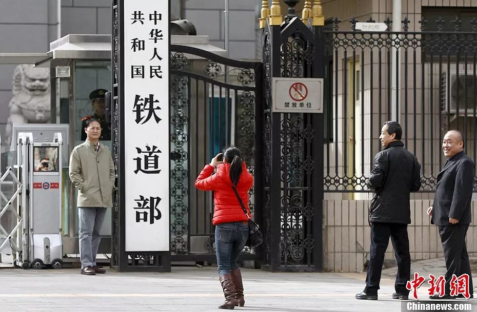 资料图:2013年3月10日,提请全国人大会议审议的国务院机构改革和职能转变方案,将不再保留铁道部,实行铁路政企分开。图为铁路系统职工在铁道部门前拍照留念。(中新社发刘关关 摄)