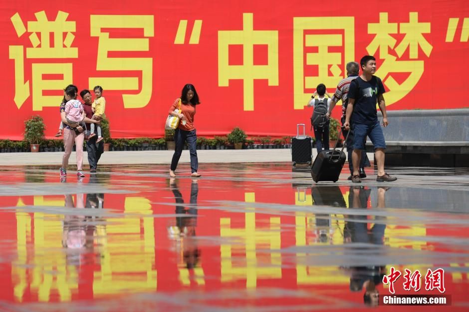 资料图:2015年5月3日,湖南长沙南站,“谱写‘中国梦’”巨大标语前的劳动者。中新社发 廖攀 摄