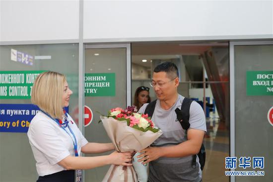8月10日，在白俄罗斯首都明斯克国际机场，首位享受免签入境政策的中国游客收到机场工作人员赠送的鲜花。新华社记者 魏忠杰 摄