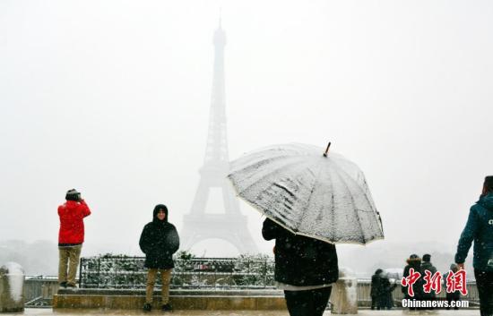 法国气象局维持对27个省份的冰雪橙色警报。受降雪影响,著名旅游景点埃菲尔铁塔6日全天关闭。图为游人6日在巴黎以埃菲尔铁塔为背景拍摄雪景。中新社记者 龙剑武 摄