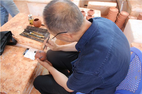 (书画大师正在紫陶壶身上作画)