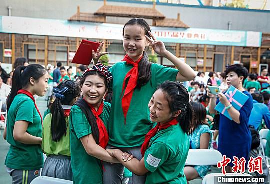 资料图：北京光明小学的两名毕业生抬着另一名同学合影。中新社发 张浩 摄