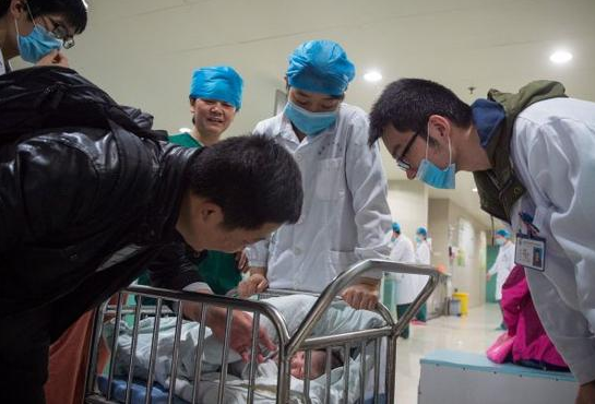 资料图片：安徽医科大学第一附属医院产房外，助产士将一个刚出生的婴儿送到父亲身边。新华社记者 郭晨 摄