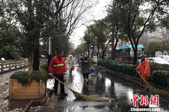 图为环卫工人正在清扫道路积雪。 崔佳明 摄