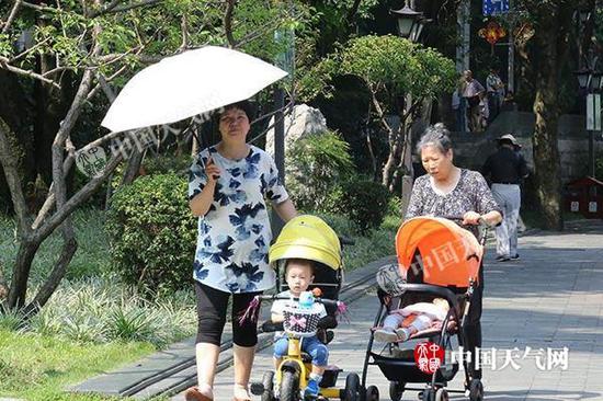 昨天,福州现今年来首轮高温,市民撑伞出行。郭超燕 摄
