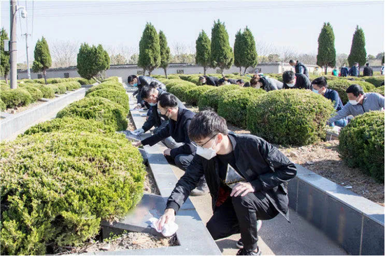 图为志愿者们在擦拭墓碑