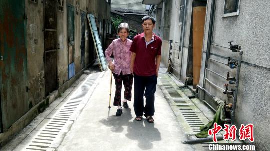 只要不下雨,每天早上8点,彭建国都会牵着母亲张喜秀出去散步。 徐志雄 摄