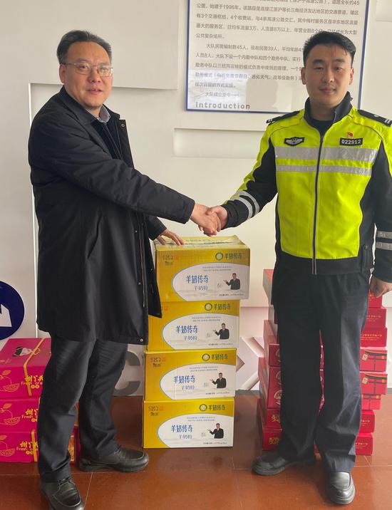 谢家学会长将羊奶粉、水果、坚果等新年慰问品送到高速一大队邵凯大队长手中。