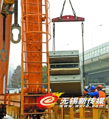 工人在将盾构管片装上龙门吊,通过地下隧道运往地铁3号线无锡火车站站的施工场地。 (张立伟 摄)
