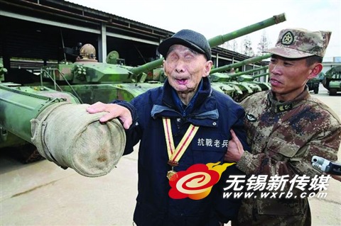 钱建民(左一)在部队官兵的搀扶下摸了坦克。