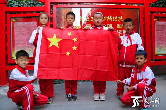 乌鲁木齐市新民路西社区,少先队员与国旗合影。