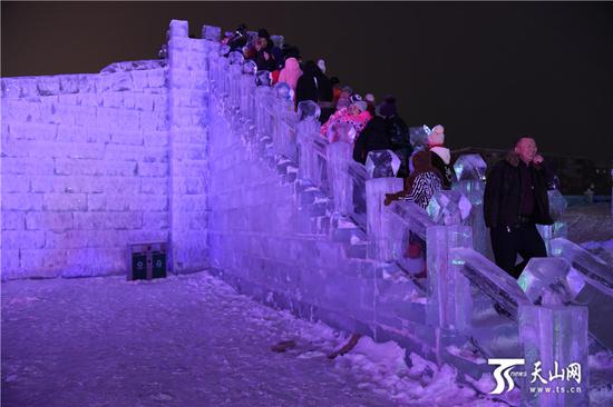 2019-11-20晚,众多游客在阿勒泰市冰雪大世界登上滑梯准备滑雪。