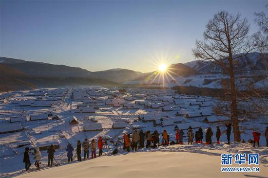 2月9日,游客在喀纳斯景区禾木雪乡拍摄落日。新华社发(雷东翔 摄)