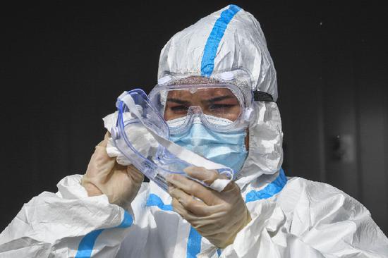 在新疆卡拉苏口岸,中方防疫工作人员为了防止护目镜起雾,正在给护目镜涂上洗洁精(10月16日摄)。
