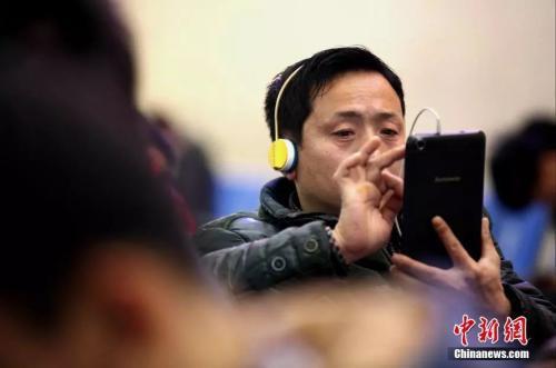 资料图:候车室内,玩手机的民众。中新社发 徐崇德 摄