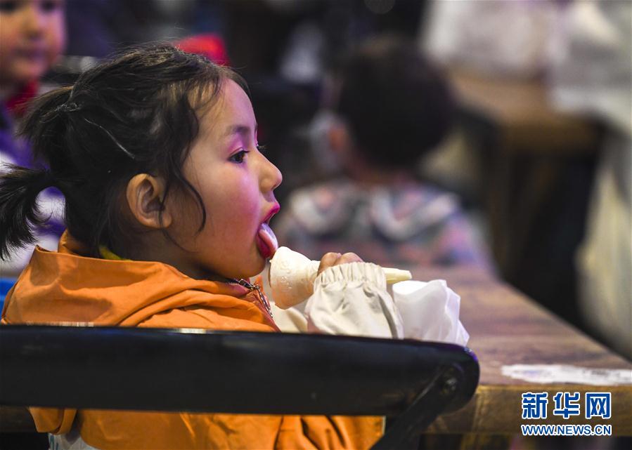 3月16日，在和田夜市环湖店，一个小朋友在品尝美食。新华社记者 赵戈 摄
