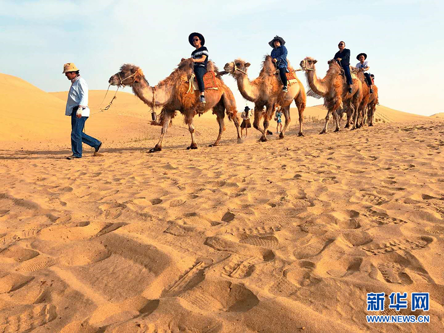 游客在罗布人村寨里骑着骆驼游览。(阿丑视界 摄)