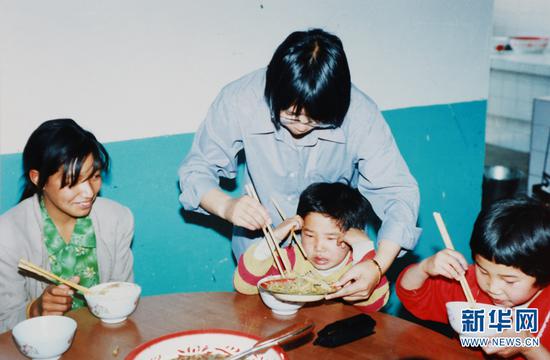 2002年,张桂梅在“儿童之家”照顾孩子们吃饭(资料图)。新华网发(华坪县融媒体中心 供图)