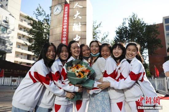 资料图:6月10日,在北京人大附中高考考点外,考生们相拥拍照留念。当日,北京市2021年高考结束。 中新社记者 赵隽 摄