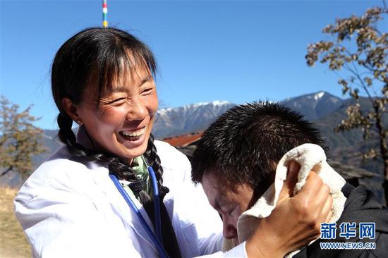 在云南怒江贡山县丙中洛镇小查腊村,管延萍(左)为村民学罗军洗头(1月14日摄)。