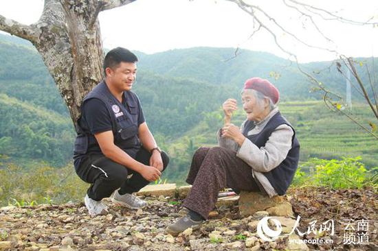 戴学江上前问候坐在村头树下晒太阳的老人。(人民网 符皓 摄)