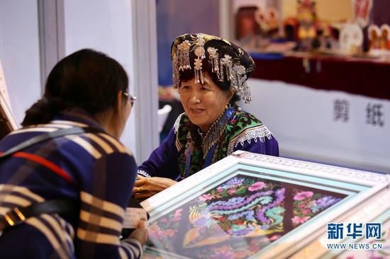 云南非遗展区,商家正在咨询洽谈。(新华网 张翼鹏 摄)